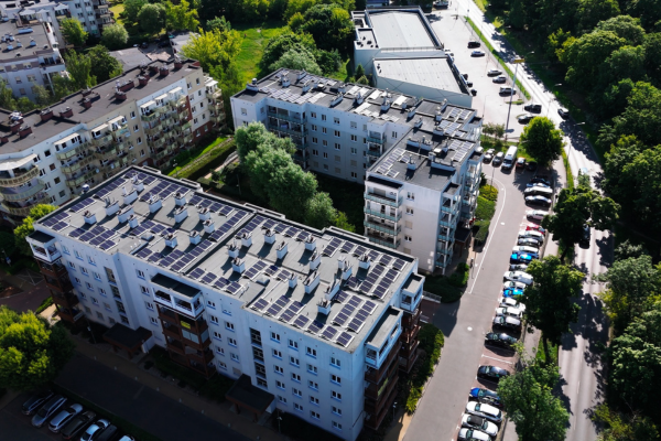 Widok z drona na osiedle bloków mieszkalnych z instalacją fotowoltaiczną na dachu