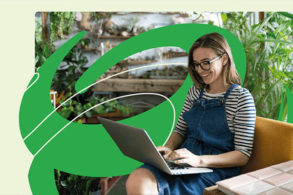 kobieta siedząca przed laptopem w otoczeniu zieleni