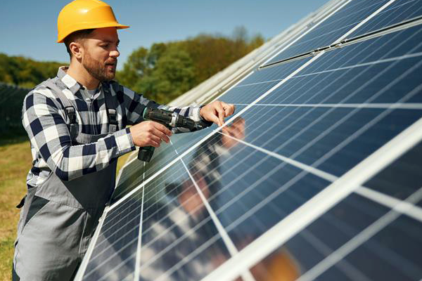 Pracownik techniczny w kasku i kamizelce ochronnej sprawdzający instalację paneli fotowoltaicznych